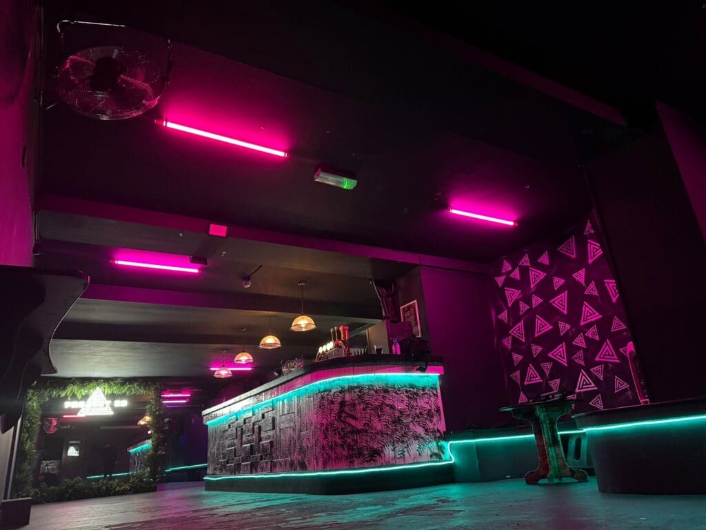 Neon-lit bar interior with geometric patterns.