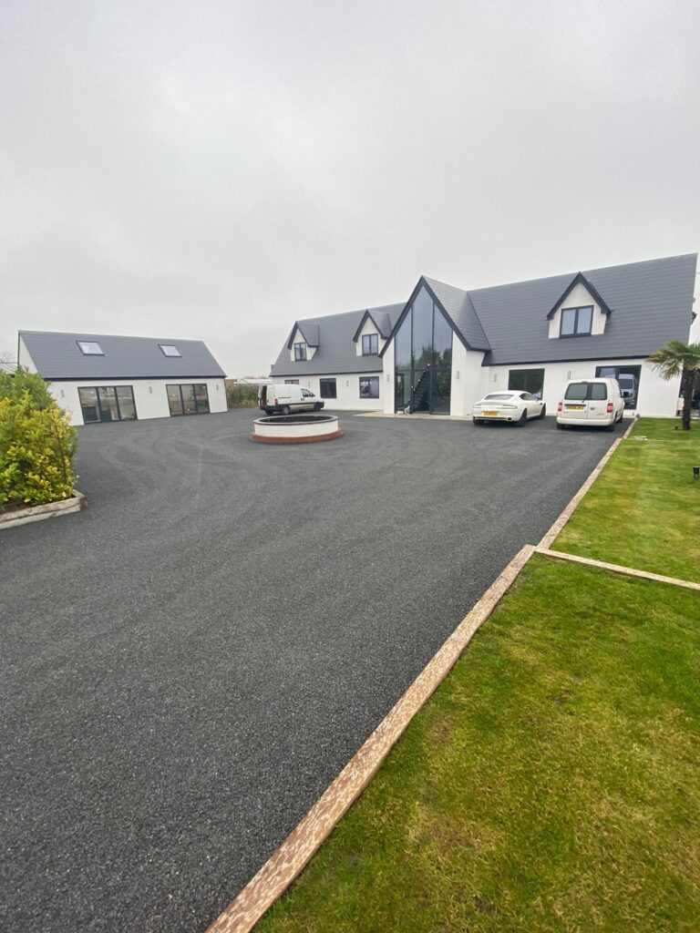 Modern house with large driveway and cars.