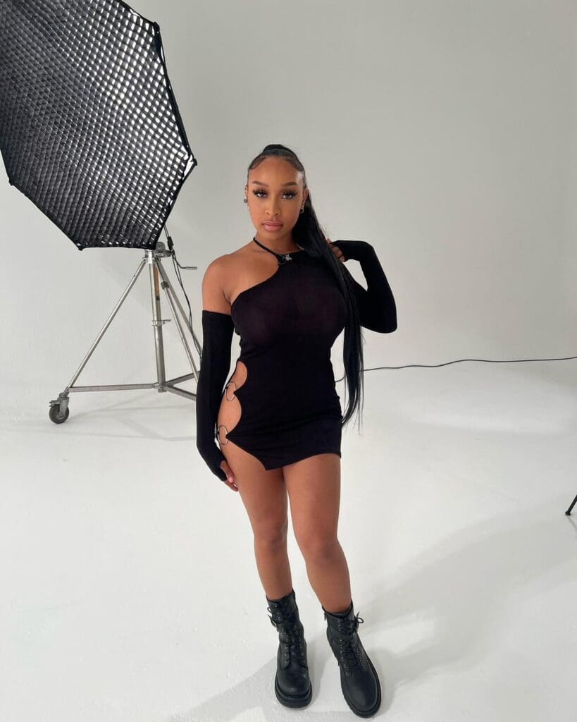 Woman in black dress posing in studio.
