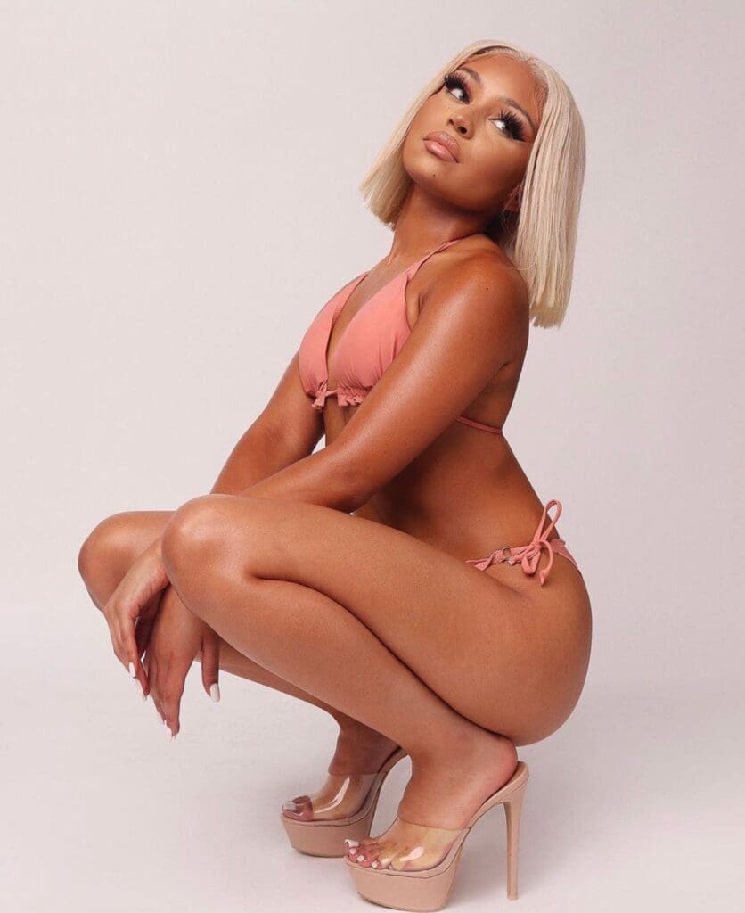Woman posing in pink bikini and heels.