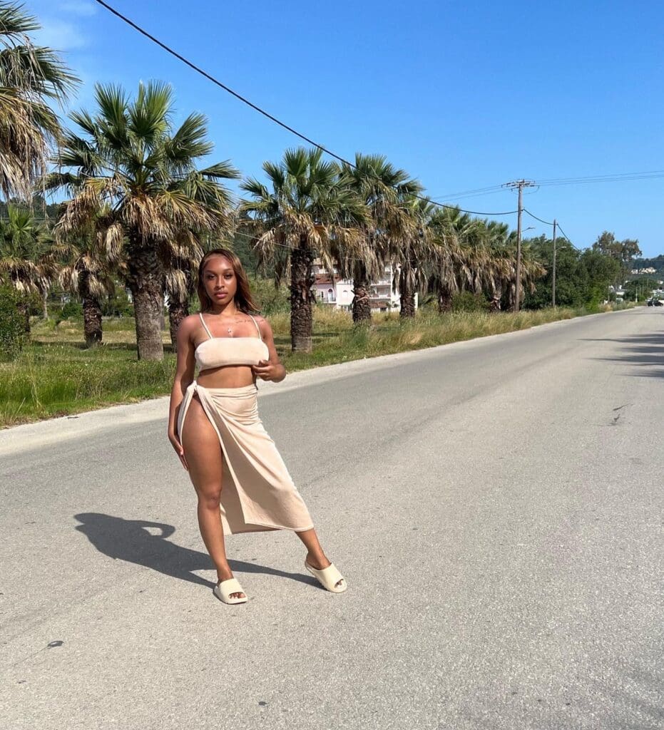 Woman posing on road lined with palm trees.
