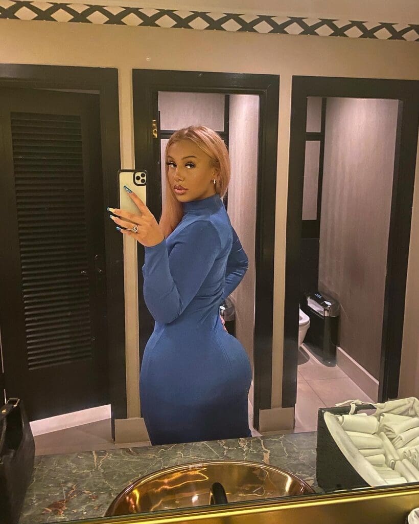 Woman taking mirror selfie in blue dress.