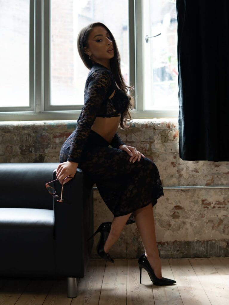 Woman posing in black lace dress indoors.