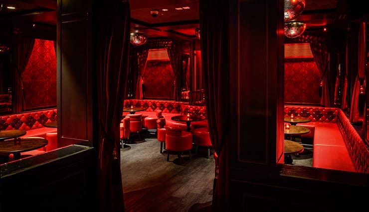 Dimly lit red-themed lounge with seating.