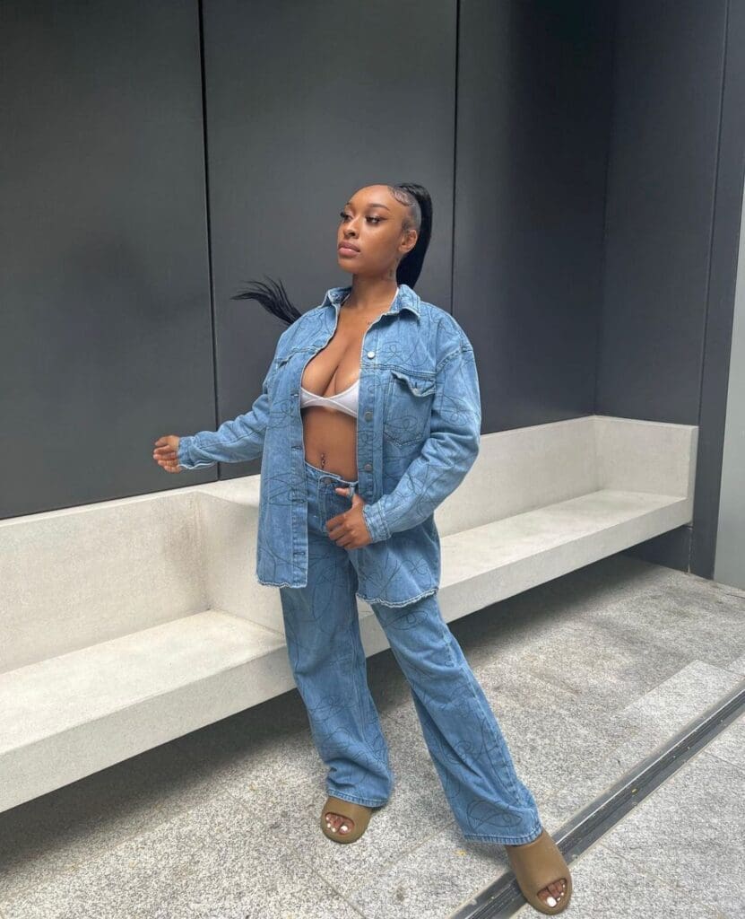 Woman in denim outfit standing confidently.