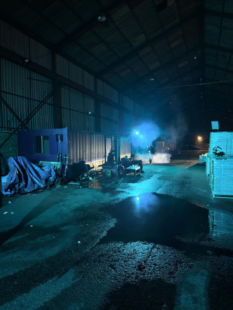 Dimly lit industrial warehouse with blue lighting.