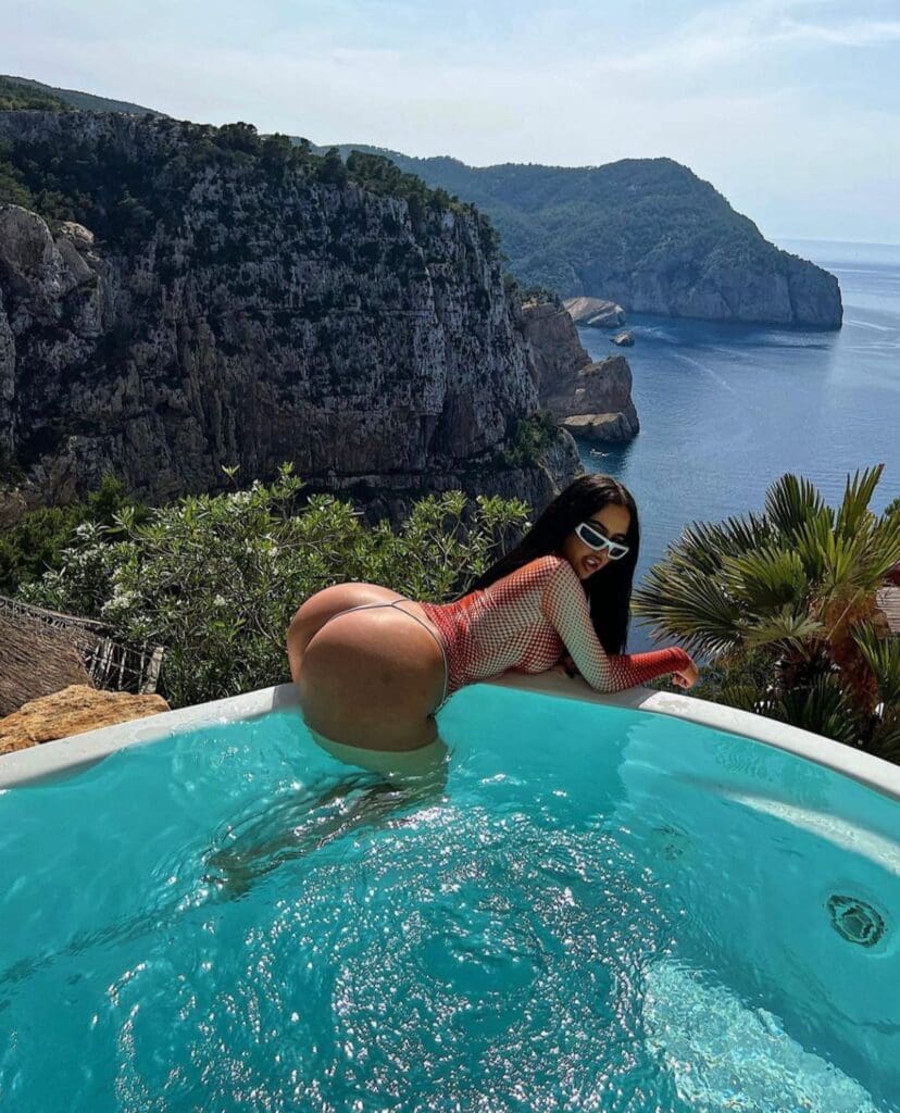 Woman in pool overlooking scenic coastline.