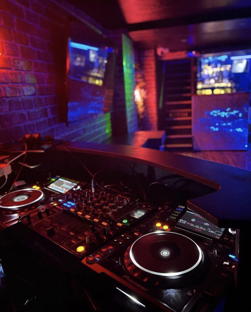 DJ booth with turntables in nightclub setting.