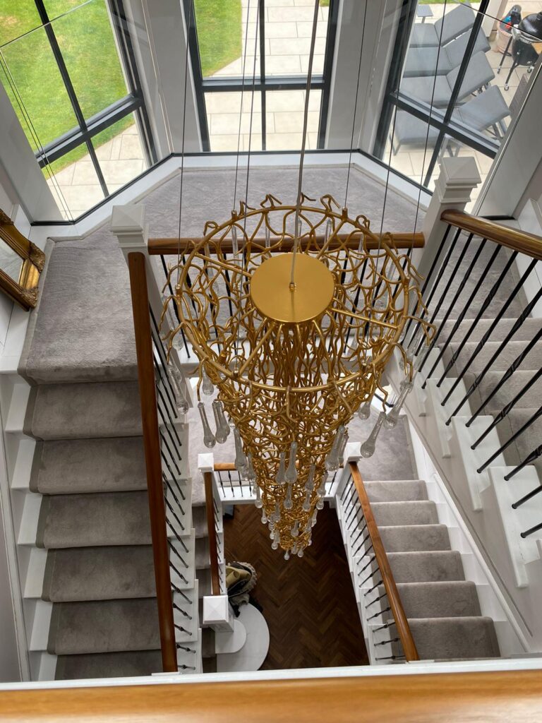 Elegant chandelier above spiral staircase.