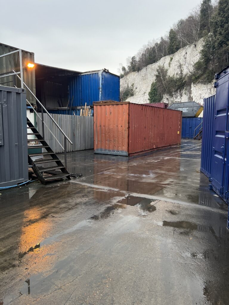 Shipping containers in a wet industrial yard.