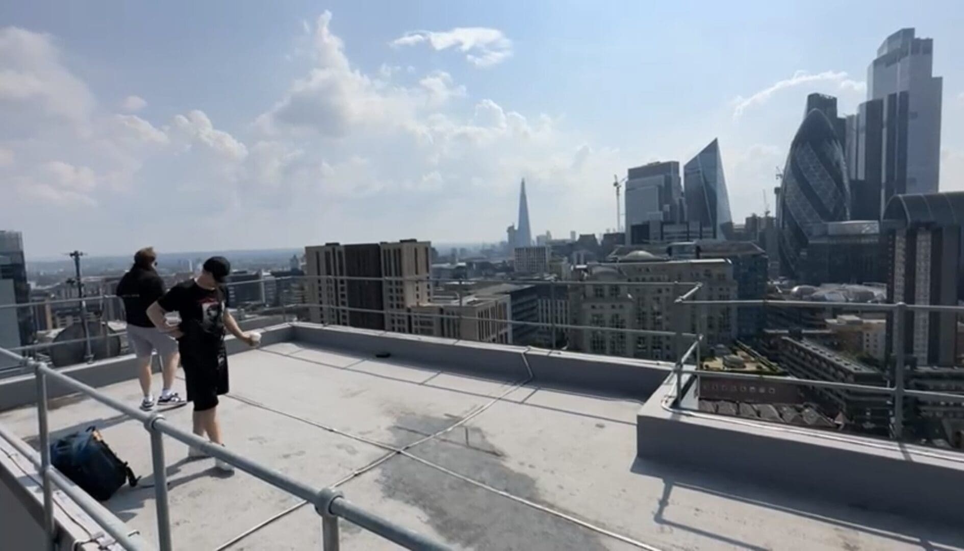 Two people on rooftop overlooking cityscape.