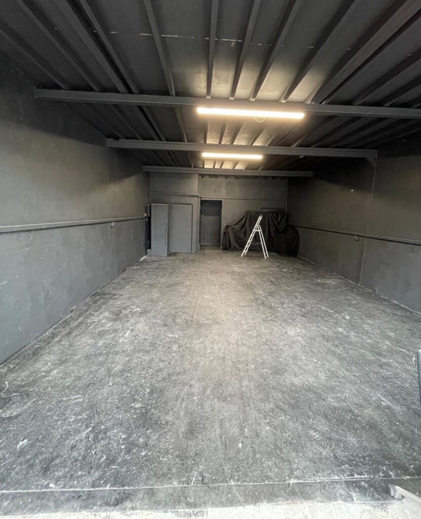 Empty garage with ladder and closed doors.