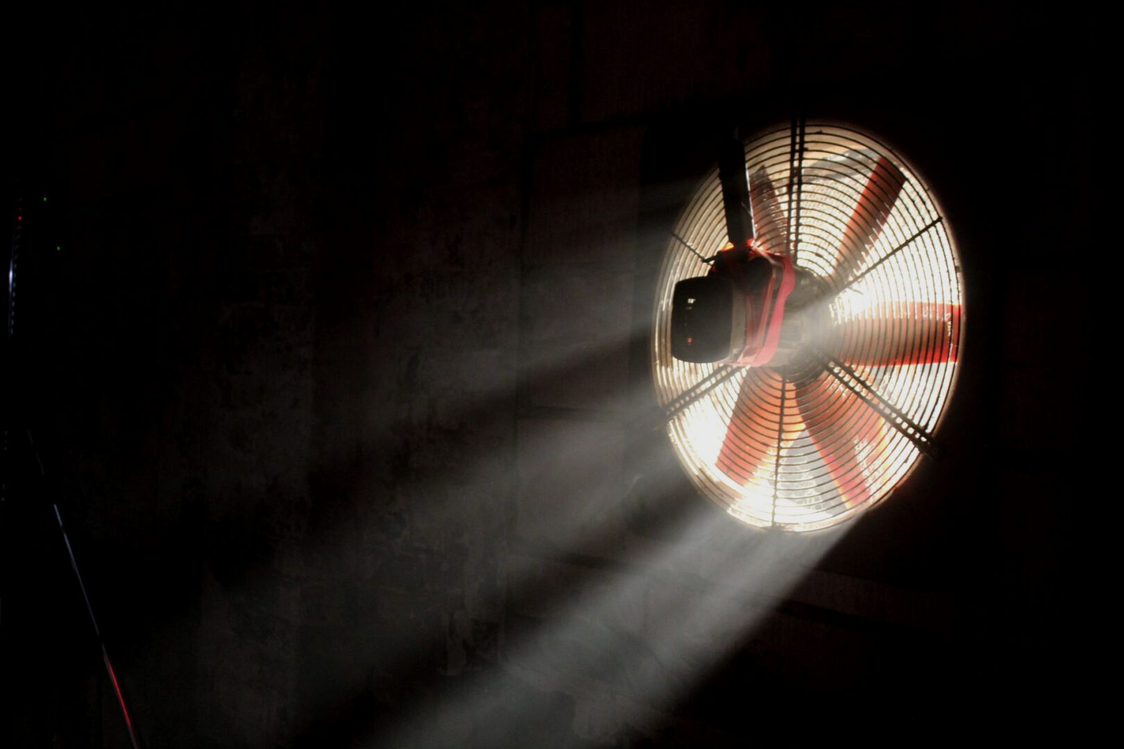 Industrial fan with light beams through blades.