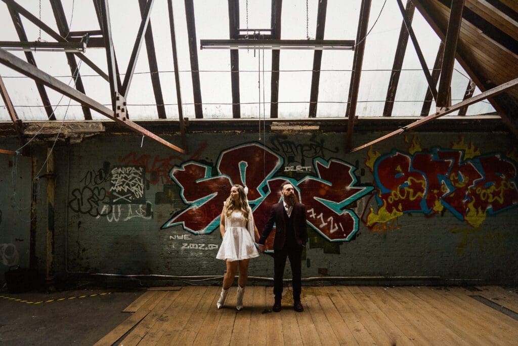 Couple standing in graffiti-covered industrial space.