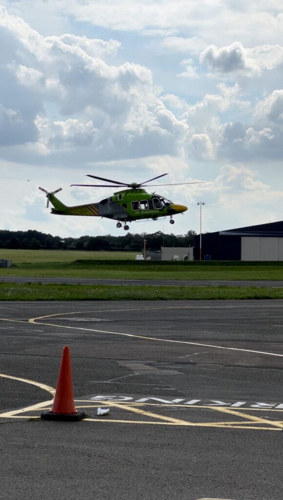 Helicopter landing near airport runway cone.