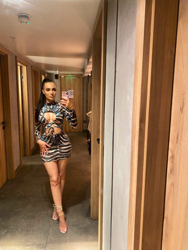 Woman taking mirror selfie in hallway.