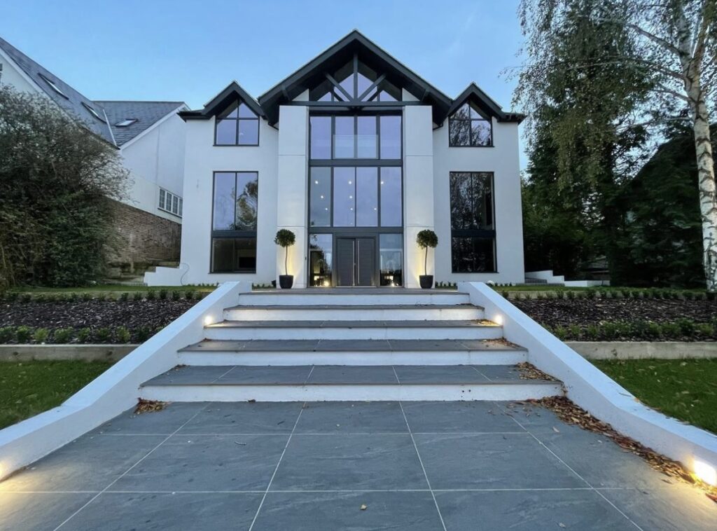 Modern house with large glass windows and stairs.