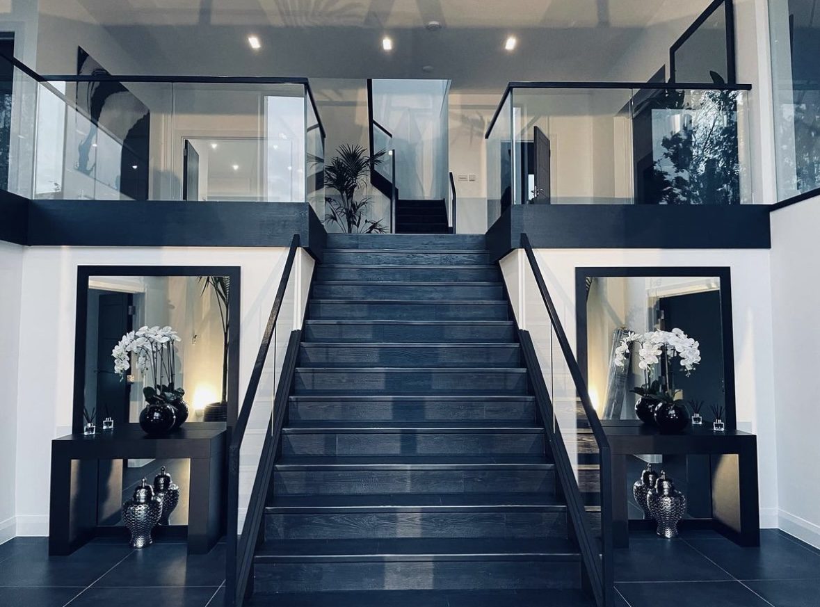Modern staircase with glass railings and decor.