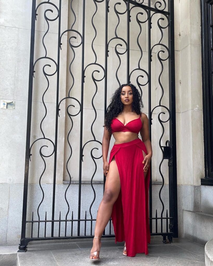 Woman in red outfit by ornate gate.