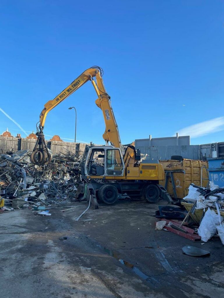 Yellow excavator at a scrapyard site.