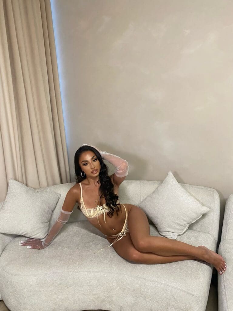 Woman posing on a couch in lingerie.