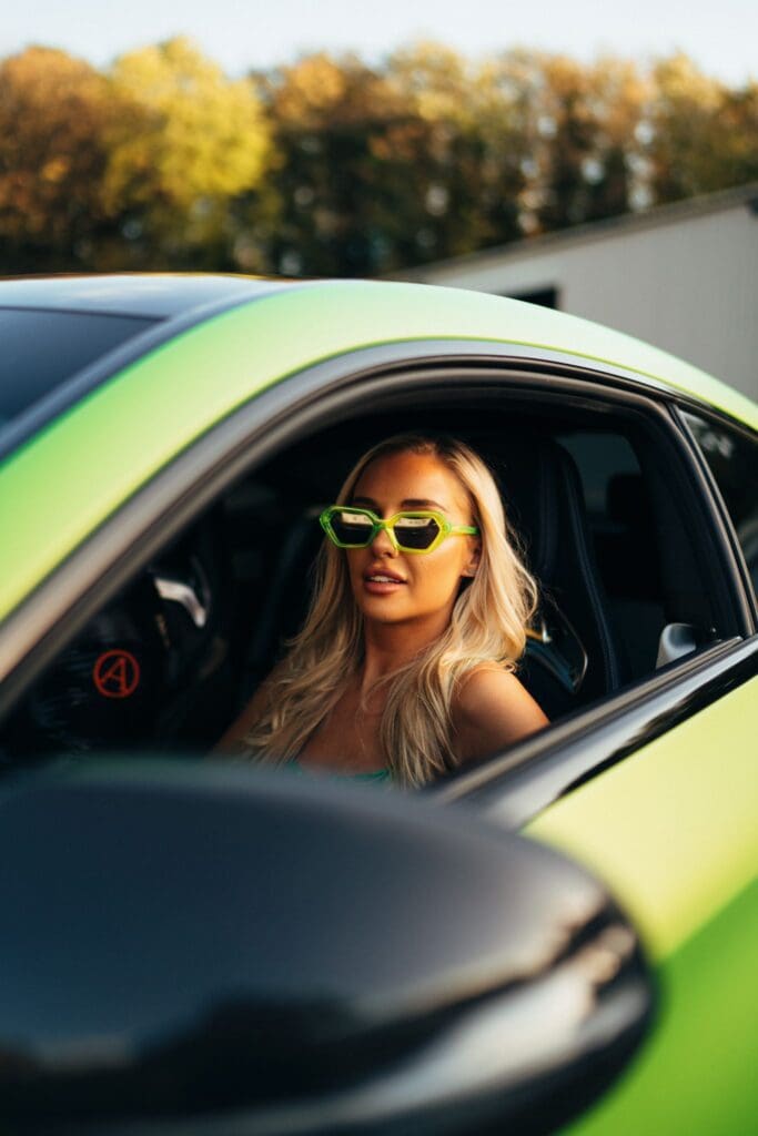 Woman with blonde hair in sporty green car.