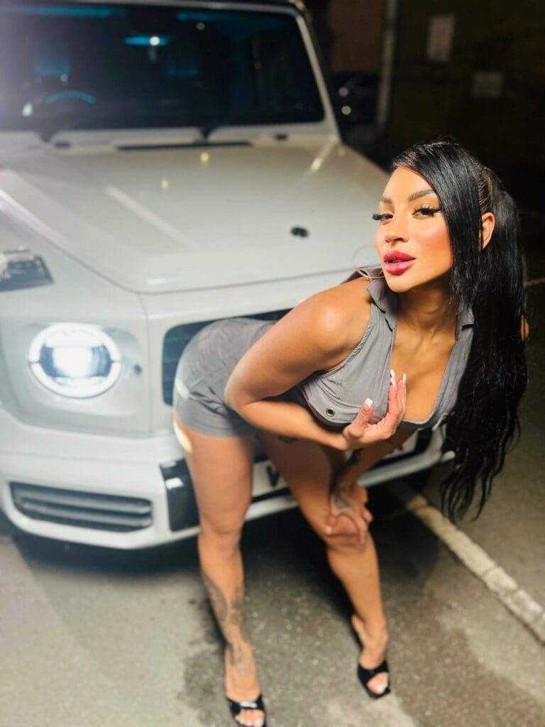 Woman posing in front of white SUV.