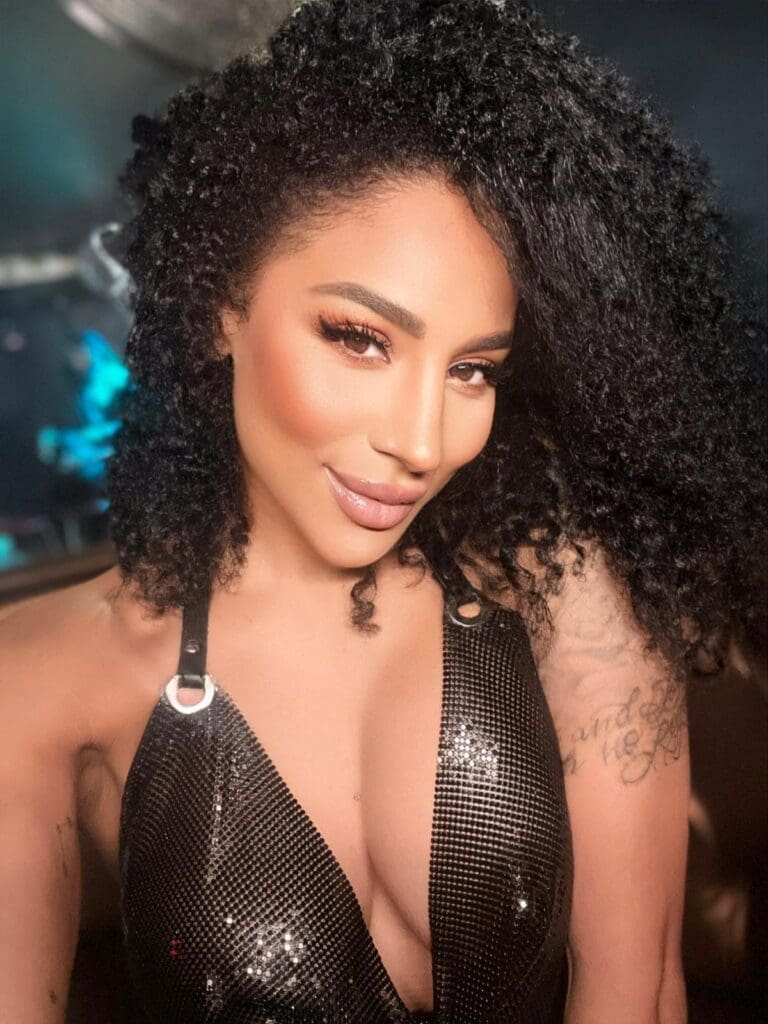 Woman with curly hair and sparkling top.