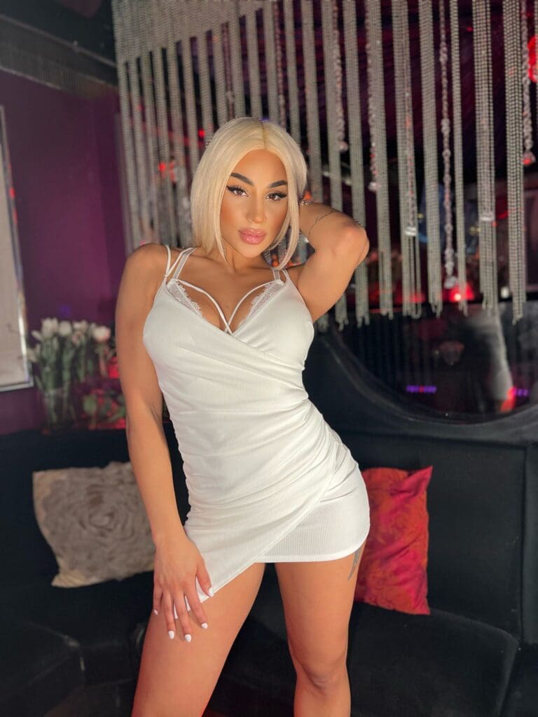 Woman in white dress posing indoors.