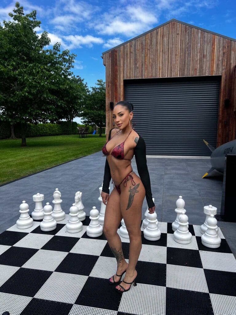 Woman in bikini standing on outdoor chessboard.