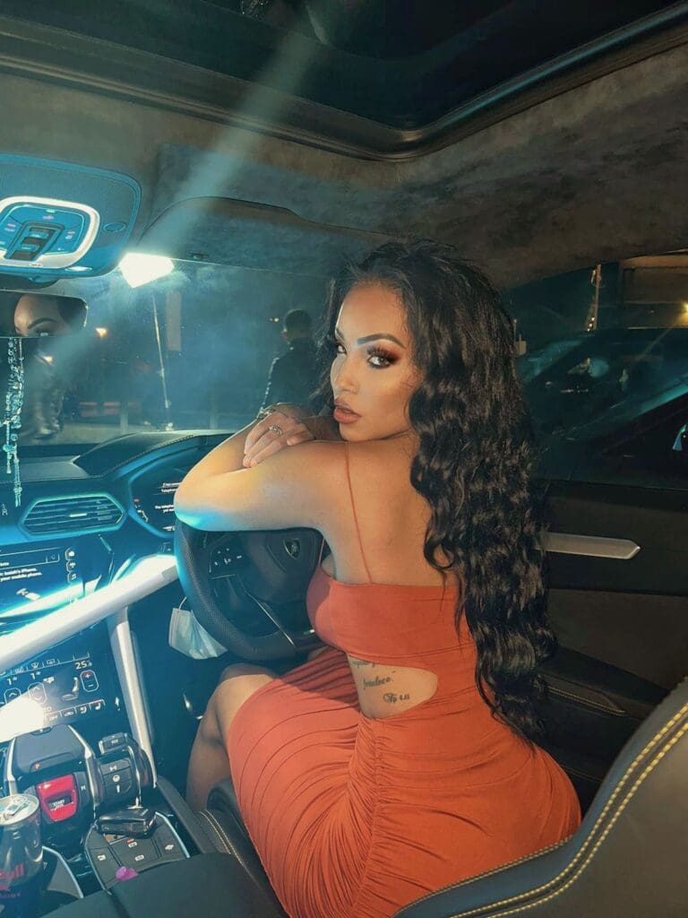 Woman in car wearing orange dress, night.