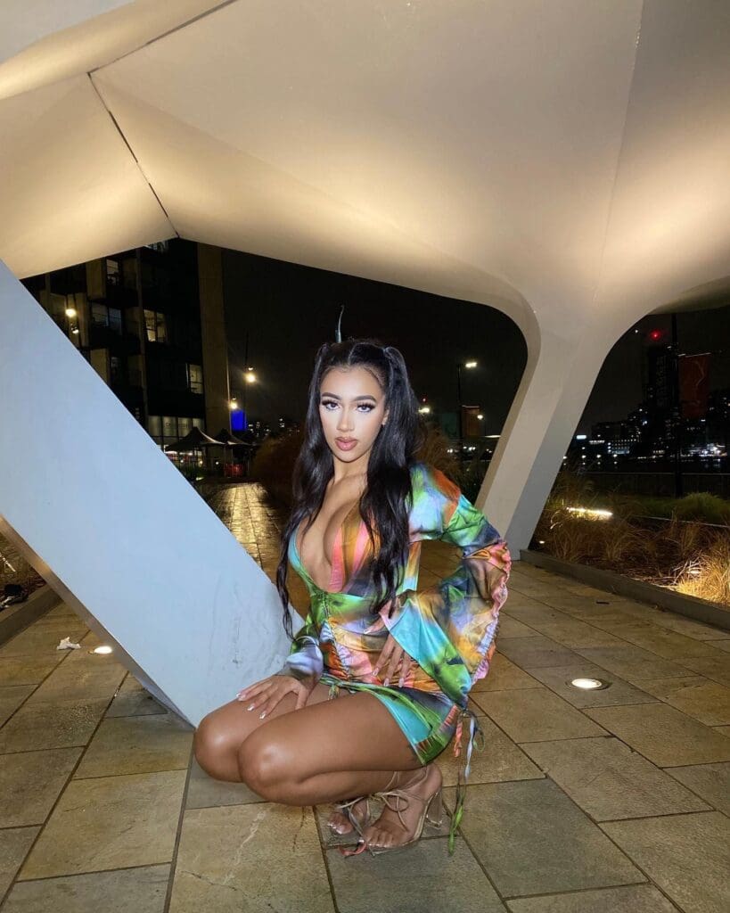 Woman kneeling outdoors in colorful dress.