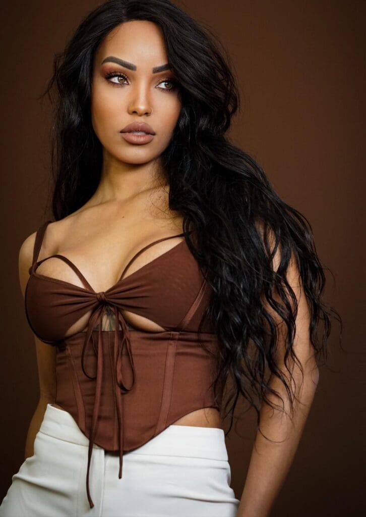 Woman in brown top and white pants.
