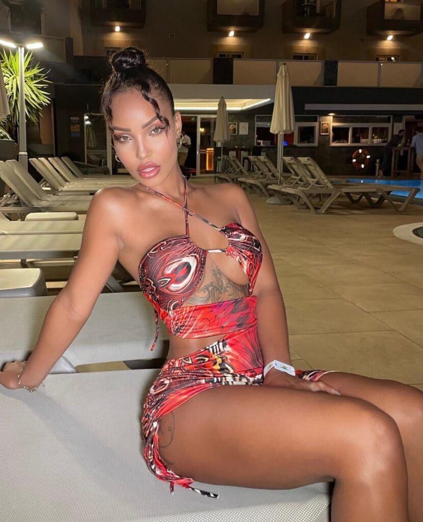 Woman in patterned swimsuit sitting poolside.