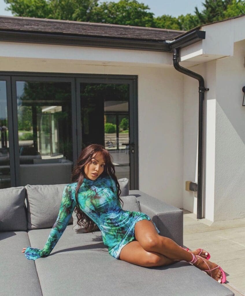 Woman lounging on outdoor sofa, vibrant dress.