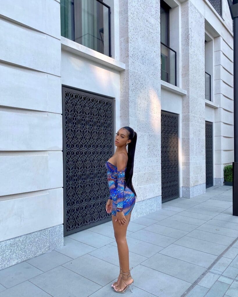 Woman in colorful dress by modern building.