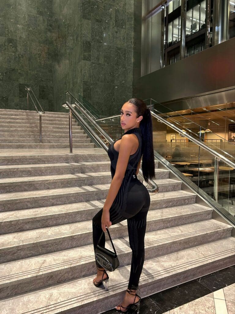 Woman posing on marble staircase, elegant attire.