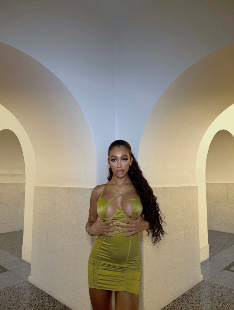 Woman in green dress, arched hallway background.
