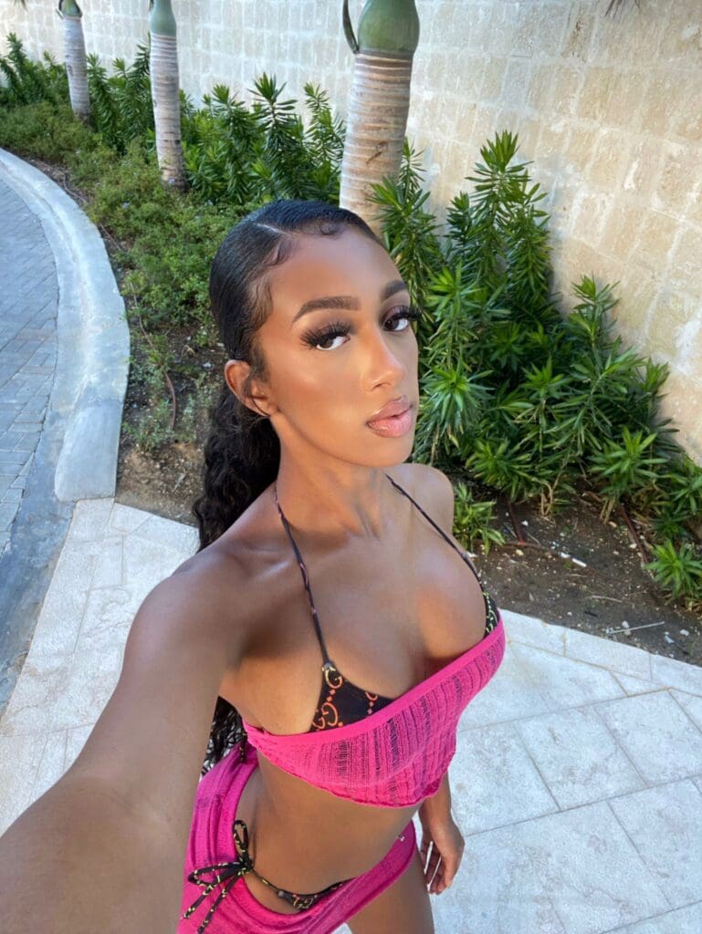 Woman in pink bikini taking selfie outdoors.