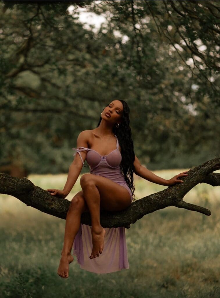 Woman in purple dress sitting on branch.