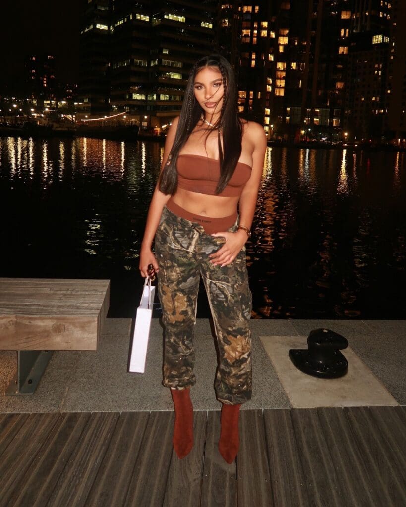 Woman posing by waterfront at night.