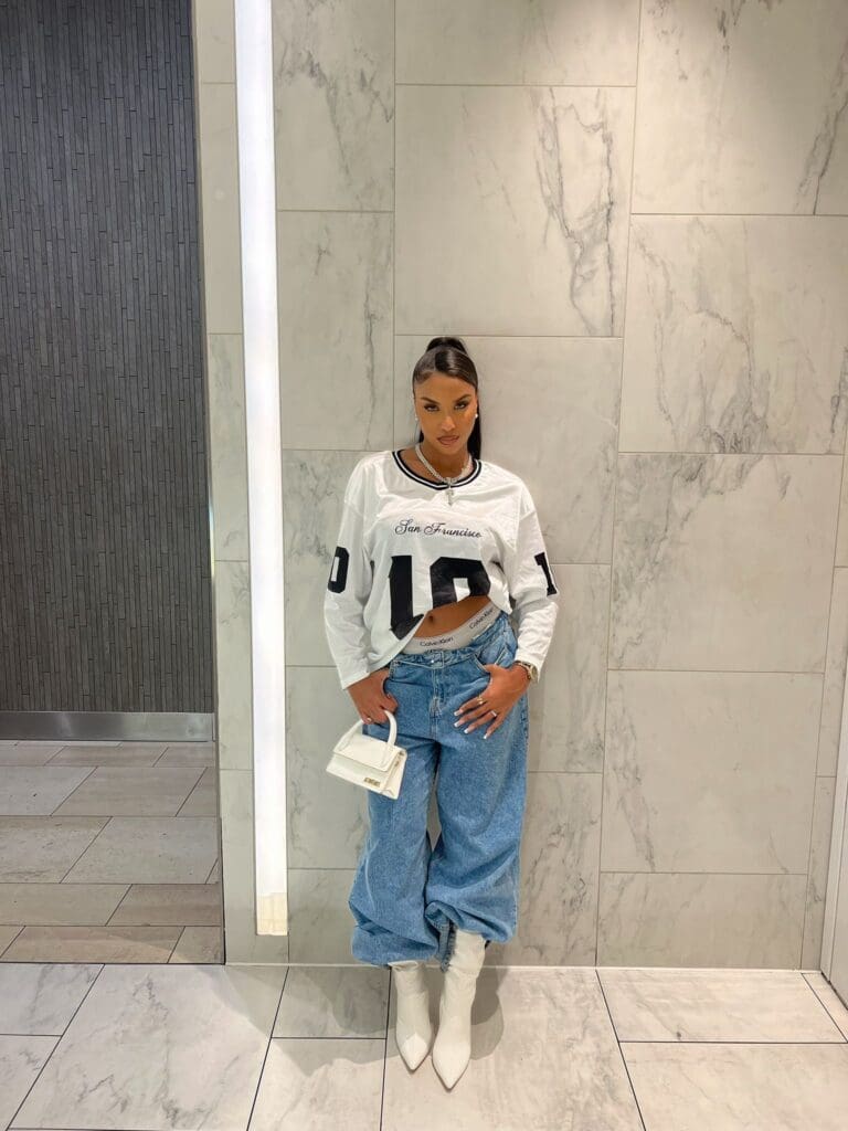 Woman in casual outfit against marble wall.