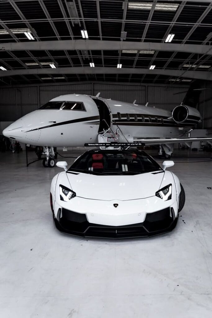 White sports car and private jet in hangar.